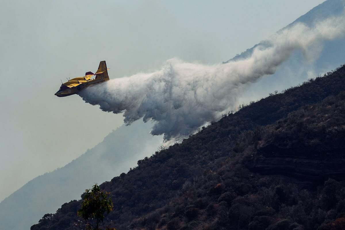 A Canadair water-bombing plane releases water on the volcano's hillside to extinguish remaining fires on July 4, 2019 a day after the Stromboli volcano erupted, on the Stromboli island, north of Sicily. - The village of Ginostra on Stromboli began sweeping away layers of ash on Thursday, the day after a dramatic volcanic eruption on the tiny Italian island killed a hiker. (AFP Photo)