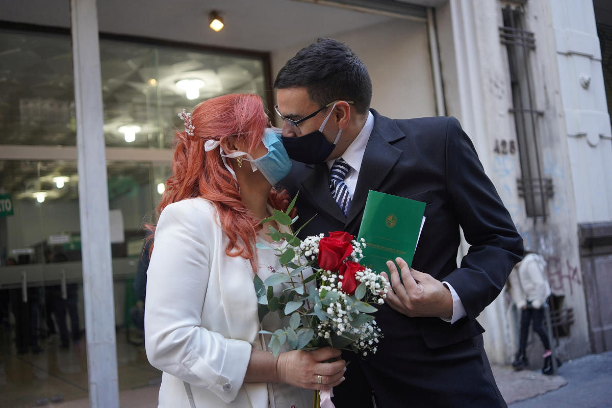 Newlyweds Laura Gomez (L) and Martin Larzabal kiss while wearing face masks after getting married at a civil status registration office amid the outbreak of the coronavirus disease (COVID-19), in Montevideo, Uruguay May 8, 2020. Credit: Reuters Photo