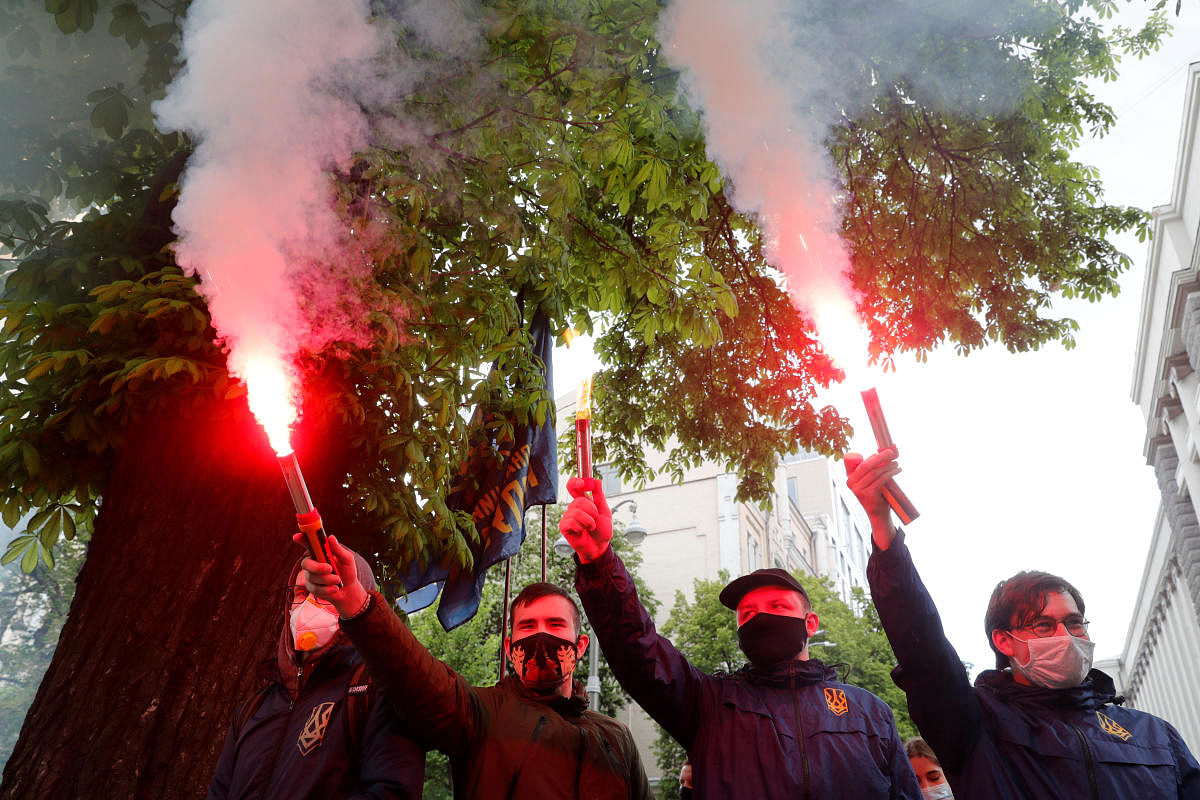 Activists of the National Corps political party wearing protective face masks burn flares during a rally demanding a resignation of the head of Ukraine's Presidential Office Andriy Yermak, outside the Mariinskyi Palace, where President Volodymyr Zelenskiy holds a news conference, amid the outbreak of the coronavirus disease (COVID-19) in Kiev, Ukraine May 20, 2020. Credit: Reuters Photo