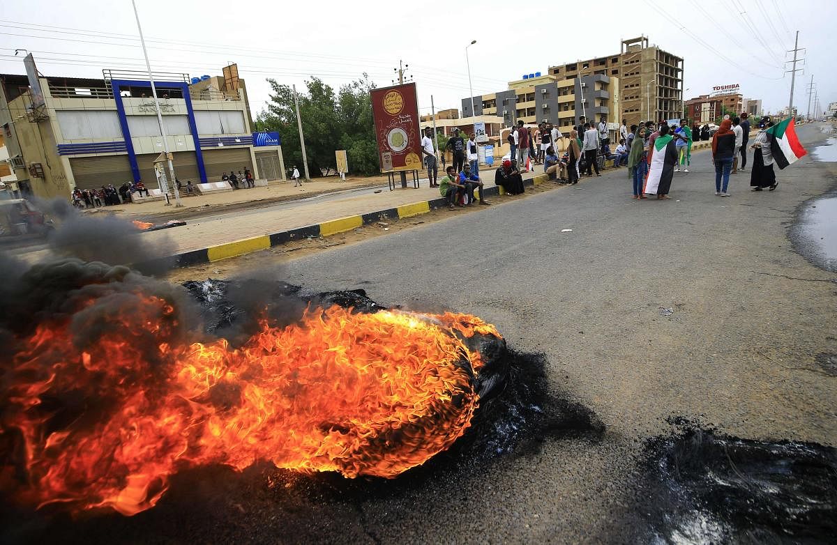 Sudanese protesters lift national flags and burn tyres as they take part in a demonstration on Sixty Street in the capital Khartoum. (AFP Photo)