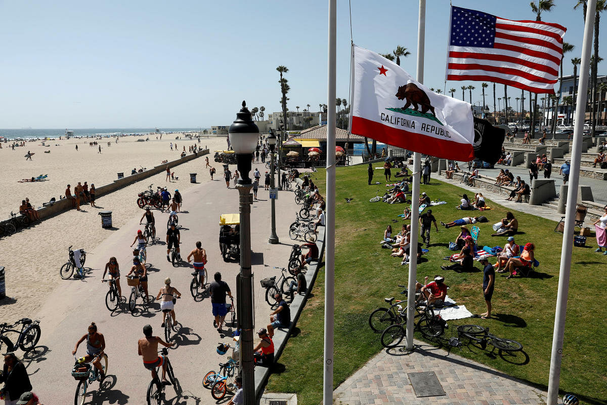 People sit at the beach as cyclists ride bicycles on Memorial Day weekend during the outbreak of the coronavirus disease (COVID-19) in Huntington Beach, California, U.S. (Reuters photo)