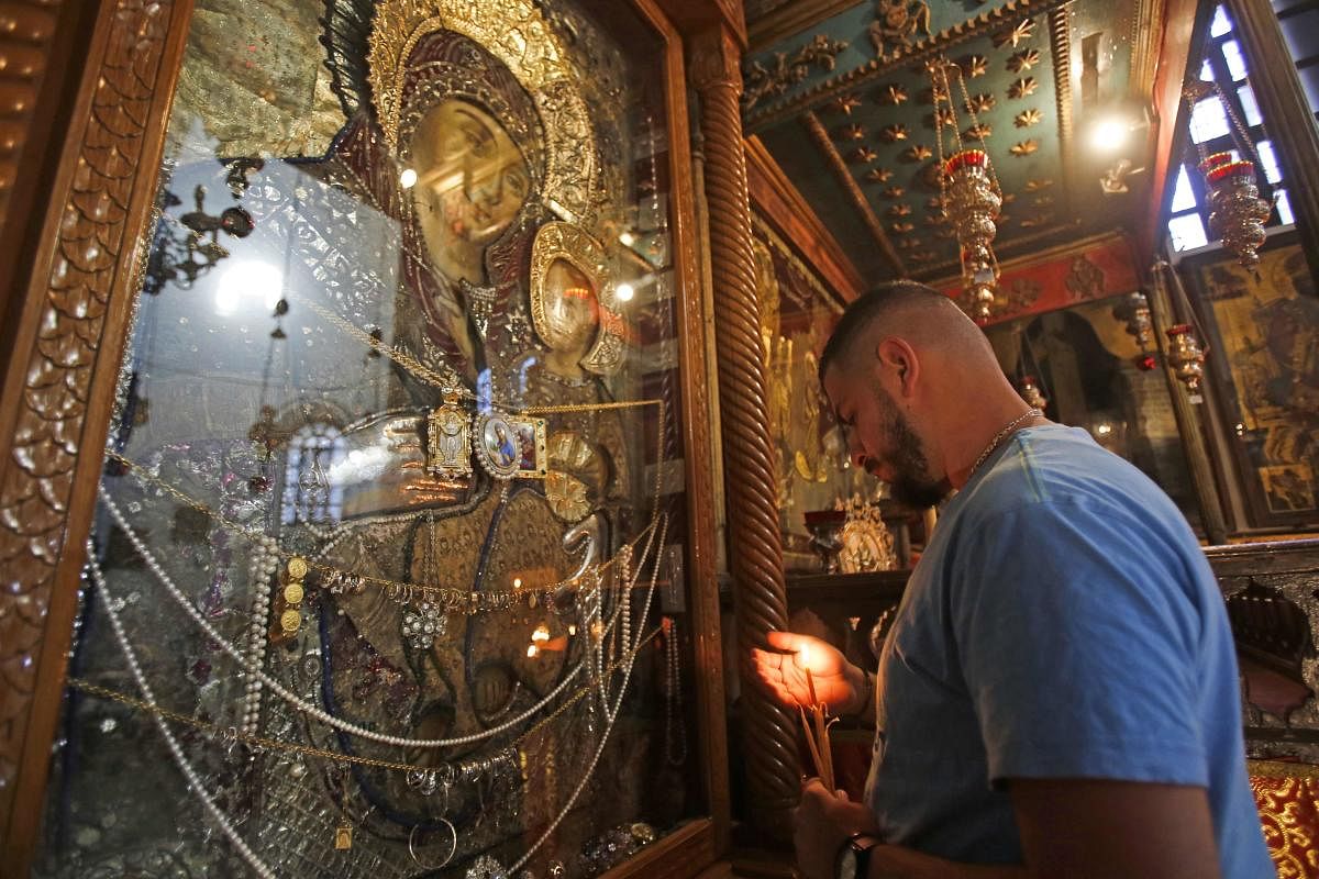 A Christian worshipper prays in Bethlehem's Church of the Nativity following its reopening as Palestinian authorities eased coronavirus restrictions in the occupied West Bank, on May 26, 2020. (Photo by Musa Al SHAER / AFP)