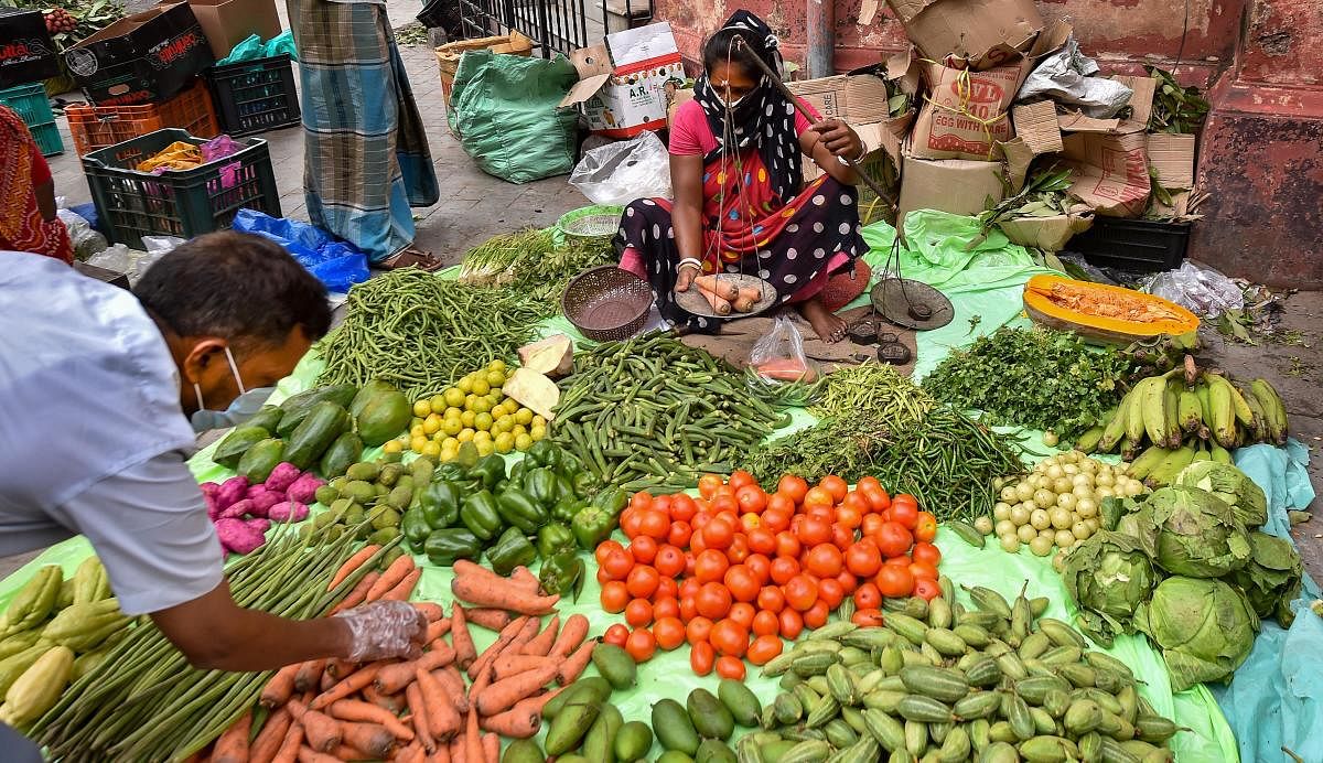 A customer selects vegetables to buy from a roadside vendor as vegetable prices soar in the city, in the aftermath of Cyclone Amphan, in Kolkata, Tuesday, May 26, 2020. (PTI Photo/Swapan Mahapatra)