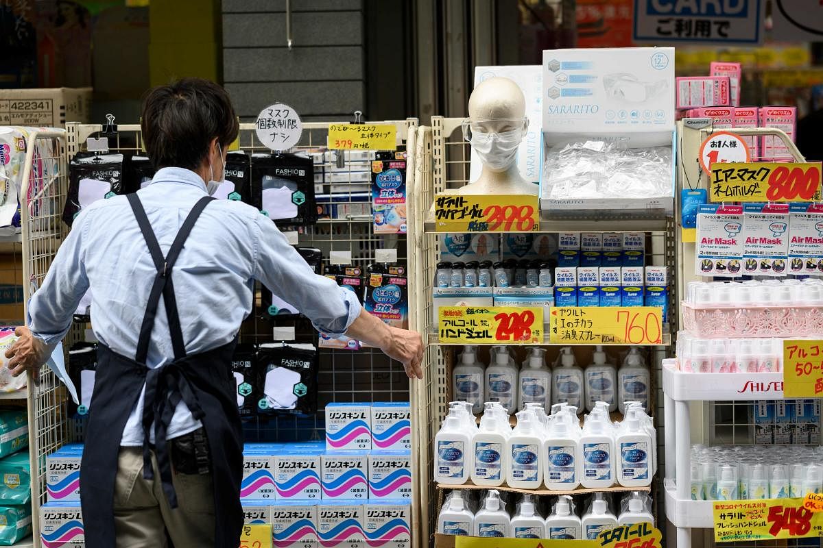 An employee adjusts shelves of face masks, protective googles and sanitiser outside a shop in Tokyo on May 26, 2020, a day after the Japanese government lifted a nationwide state of emergency. (AFP Photo)