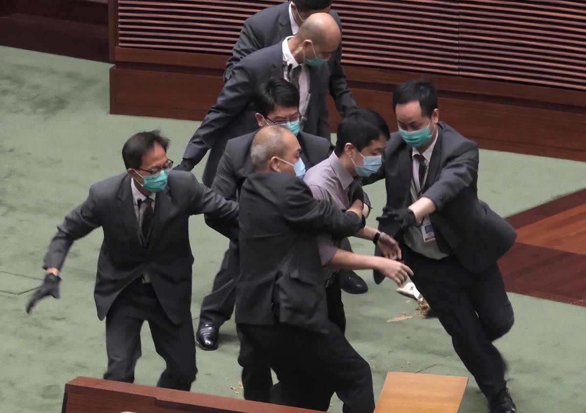 Pro-democracy lawmaker Ted Hui, center, struggles with security personnel at the main chamber of the Legislative Council during the second day of debate on a bill that would criminalize insulting or abusing the Chinese anthem in Hong Kong. AP/PTI