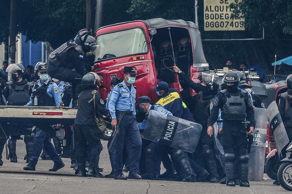 Honduran riot police members confiscate a mototaxi during a protest of taxi and mototaxi drivers demanding food and an economic aid from Juan Orlando Hernandez government, in Tegucigalpa. AFP