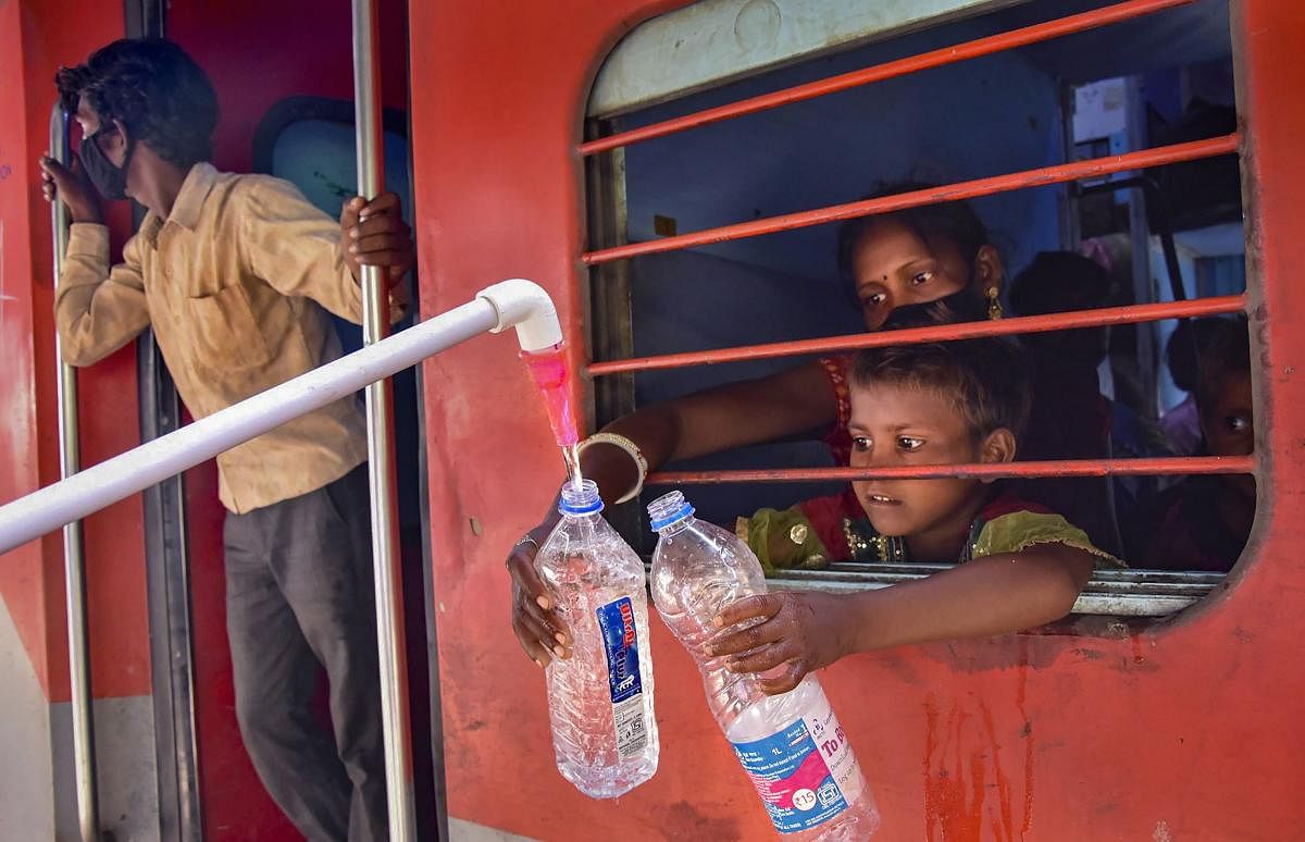 Cadets of Scouts & Guides provide drinking water to the migrants sitting in a Shramik Special train for their native places, during ongoing COVID-19 lockdown, at Mathura Railway Station. PTI