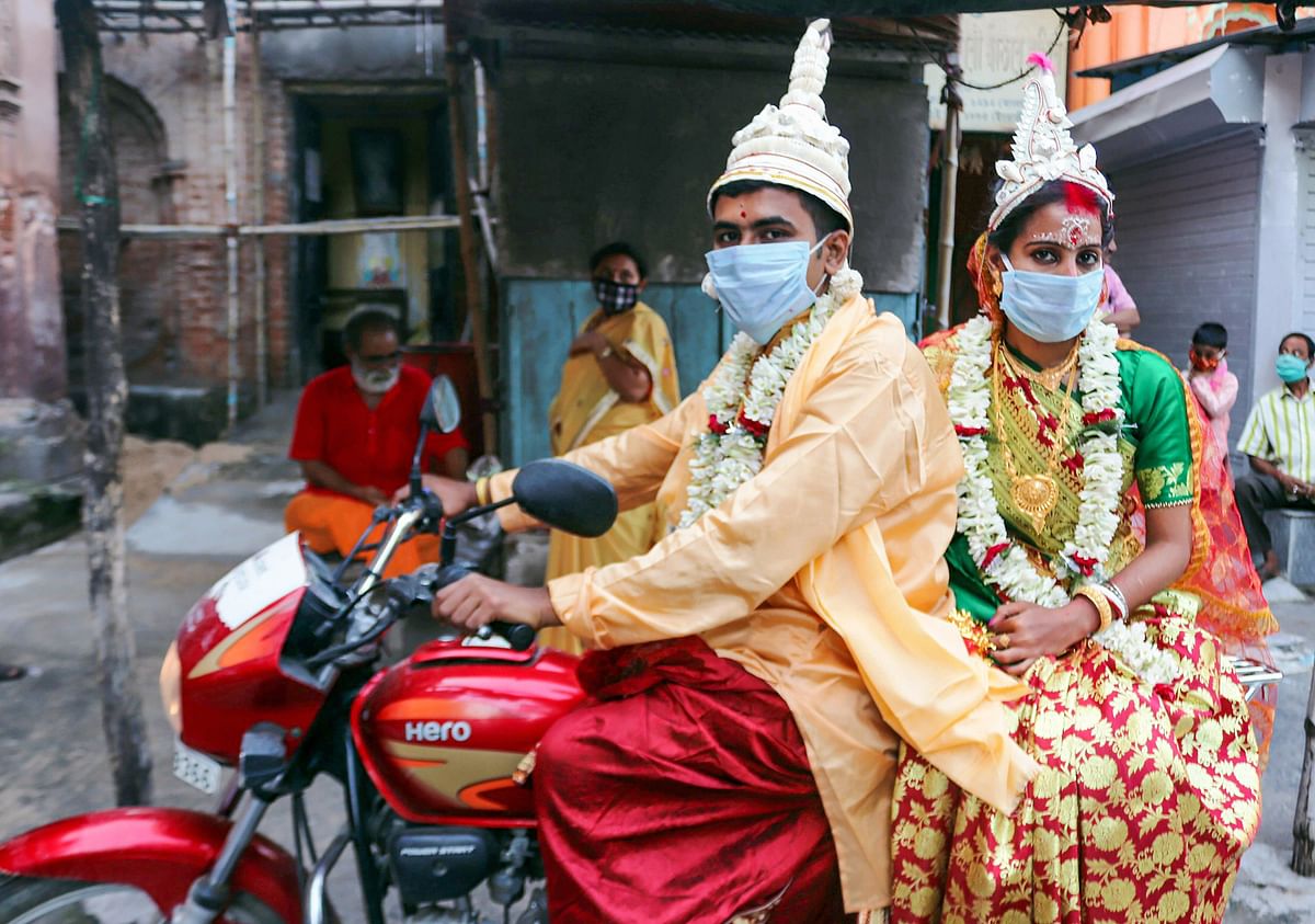 A newly married couple rides a bike after performing rituals at Sarbamangala Mandir, during the ongoing COVID-19 lockdown, in Burdwan district. (PTI Photo)