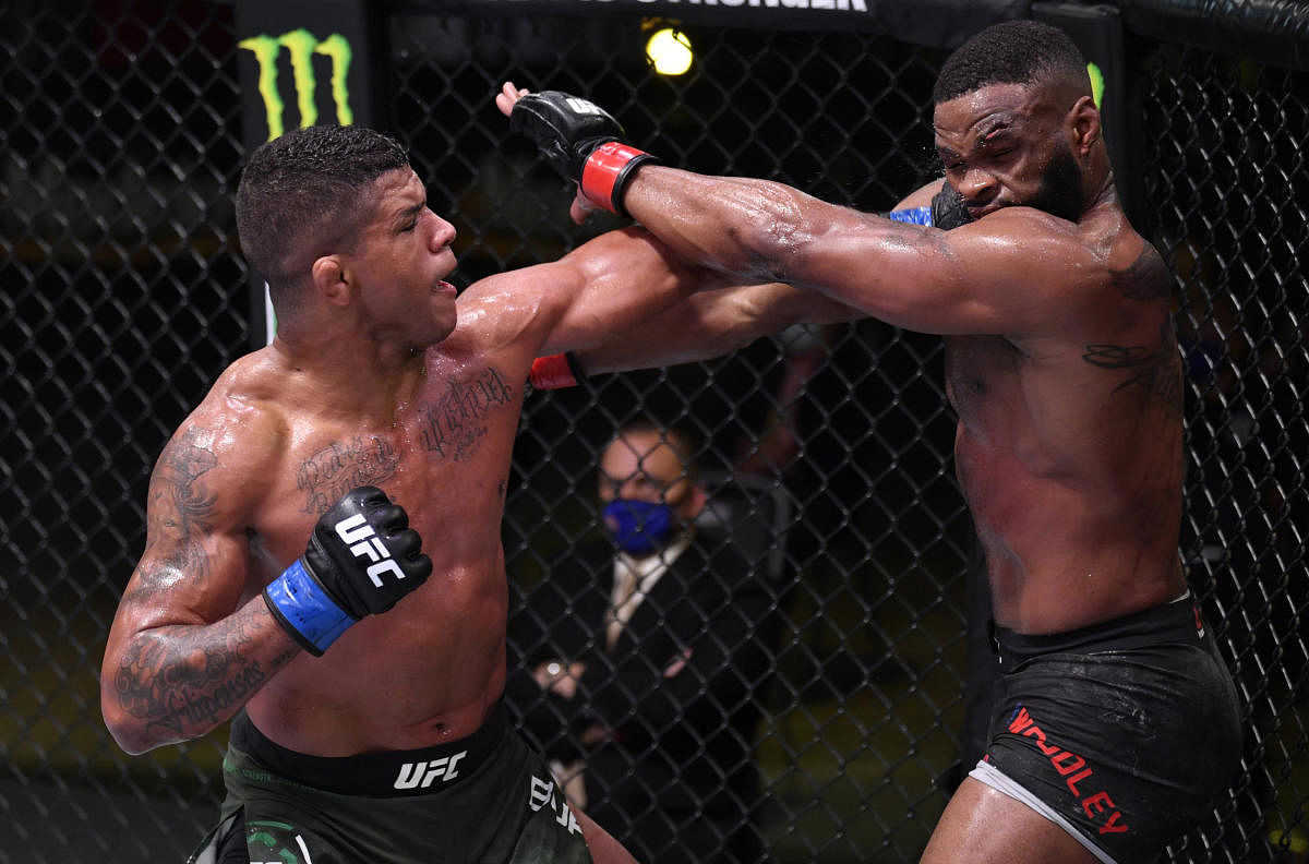 Las Vegas, NV, USA; Gilbert Burns of Brazil (blue gloves) punches Tyron Woodley (red gloves) in their welterweight fight during UFC Fight Night. Mandatory Credit: Jeff Bottari/Zuffa via USA TODAY Sports