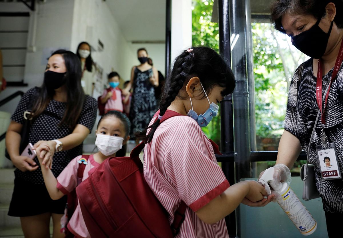 Children wearing protective face masks sanitise their hands as they attend preschool classes at St James' Church Kindergarten as schools reopen amid the coronavirus disease (COVID-19) outbreak in Singapore. (Credit: Reuters Photo)
