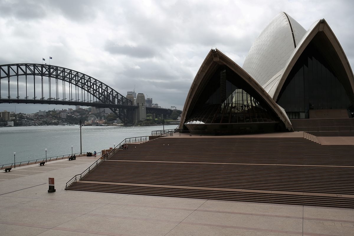 People are seen on the nearly deserted steps of the Sydney Opera House, in the wake of New South Wales implementing measures shutting down non-essential businesses and moving toward harsh penalties to enforce self-isolation. (Credit: Reuters File Photo)