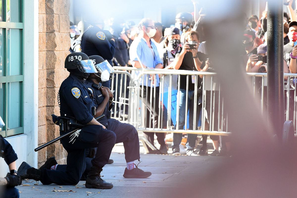 San Francisco police officers kneel after a crowd of protesters called for them to