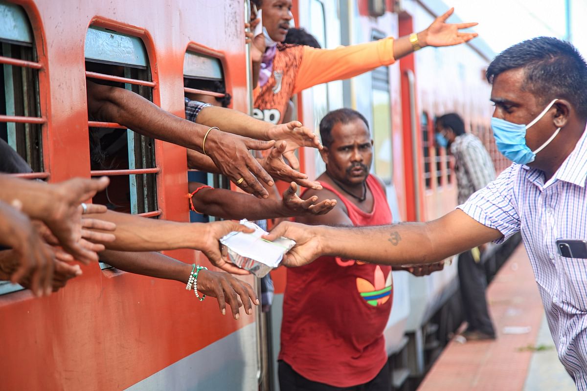 A volunteer distributes food to migrants traveling by train to their native places, during the ongoing COVID-19 nationwide lockdown, in Kanyakumari district. (PTI Photo)