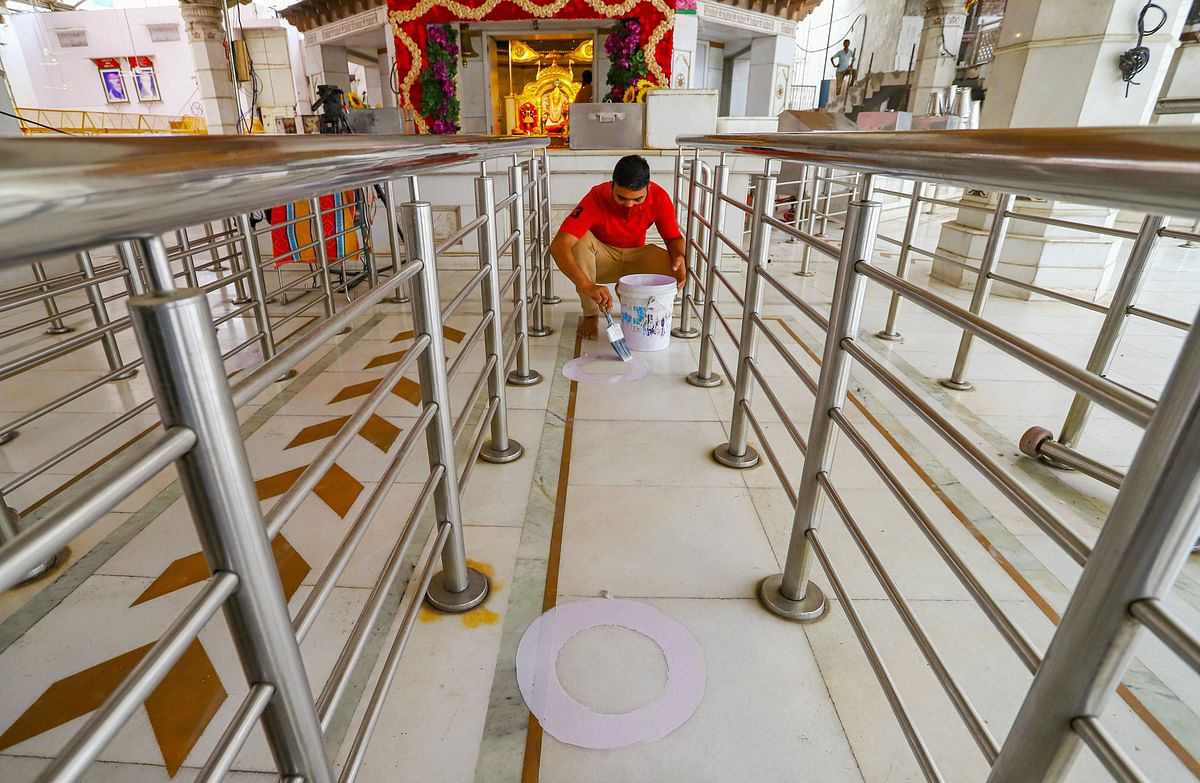 A worker paints circles on the floor of Jhandewala Devi Mandir to help maintain the social distancing norms, ahead of its reopening, in New Delhi. (PTI Photo)