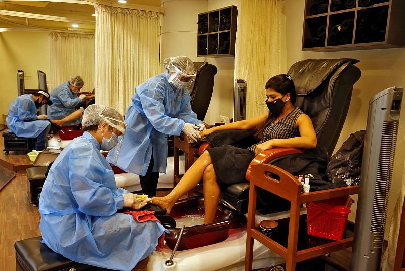Beauticians wearing protective gear tend to their customers inside a parlor at a shopping mall after authorities allowed the reopening of malls, during an extended nationwide lockdown to slow the spreading of the coronavirus disease (COVID-19), in Ahmedabad. Credit: Reuters Photo