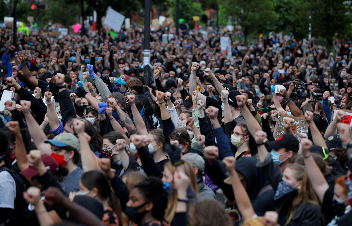 Demonstrators raise their fists as they take a knee for 8 minutes 46 seconds, the length of time George Floyd was held down with a knee on his neck by a Minneapolis Police officer, during a protest against racial inequality in the aftermath of George Floyd's death, in Boston, Massachusetts, U.S. Credit/Reuters Photo