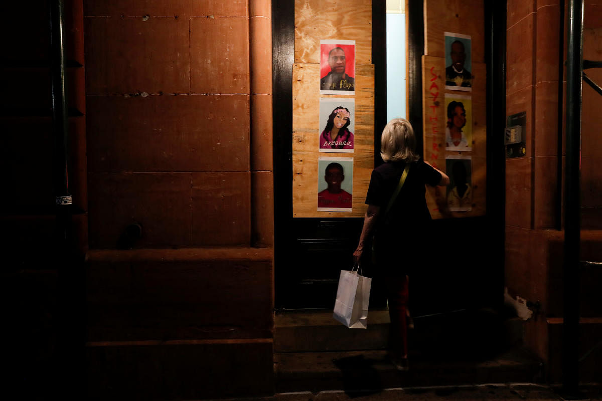 A woman enters a building pasted with pictures of George Floyd and other victims of police violence, during ongoing protests against racial inequality in the aftermath of his death in Minneapolis police custody, in New York City, New York, U.S. Credit/Reuters Photo