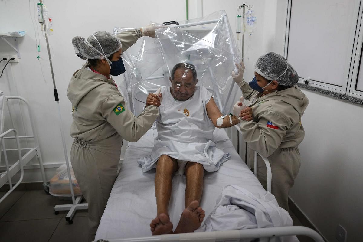 Health workers assist a COVID-19 patient at the Gilberto Novaes Municipal Hospital in Manaus, Brazil. Credit/AFP Photo