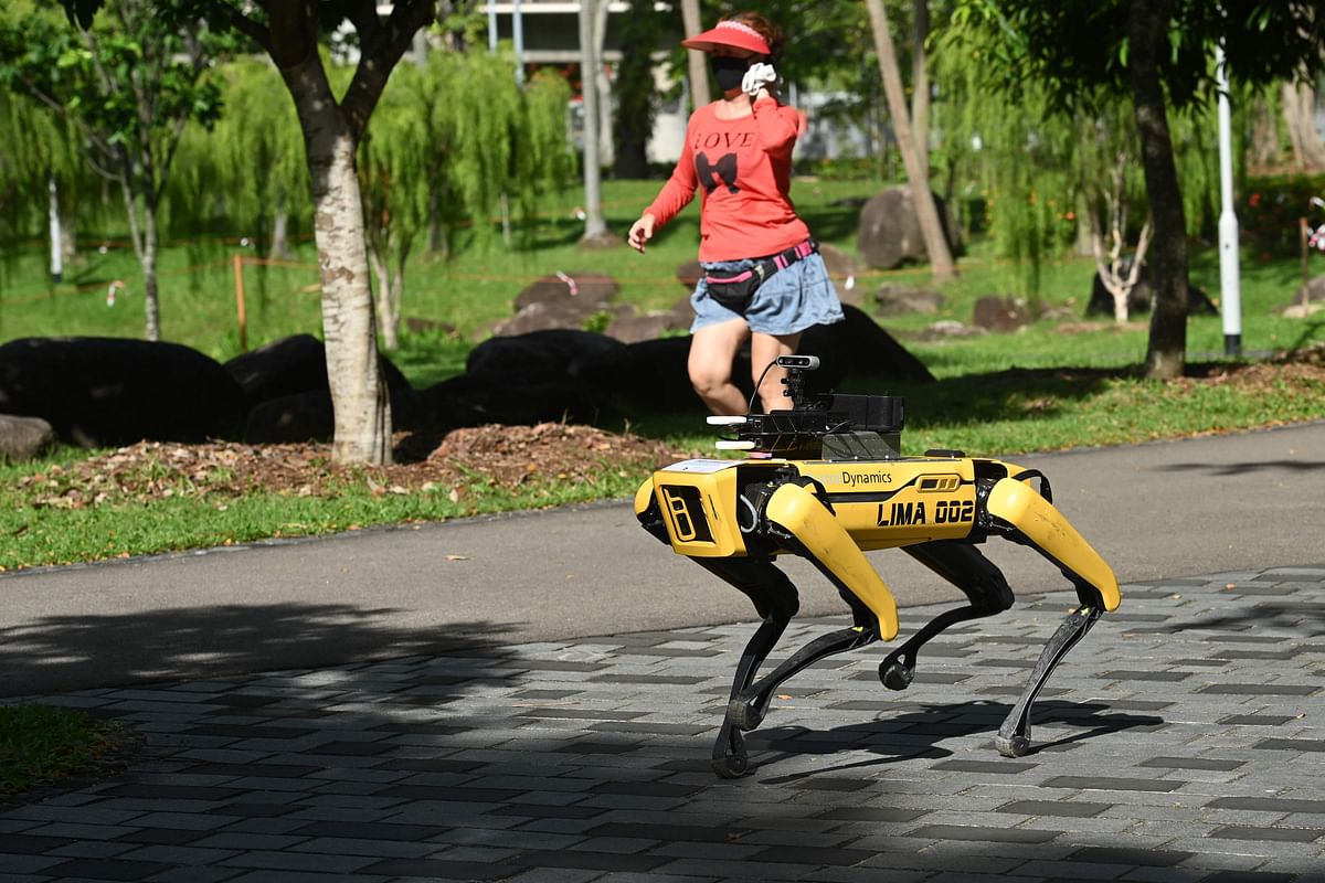 In this file photo taken on May 8, 2020 a woman jogs past a four-legged robot called Spot, which broadcasts a recorded message reminding people to observe safe distancing as a preventive measure against the spread of the COVID-19 novel coronavirus. Credit: AFP Photo