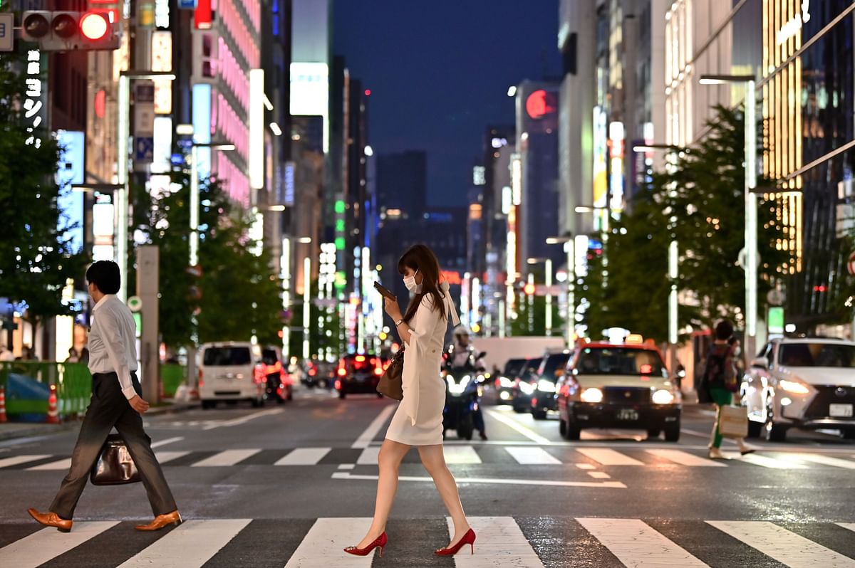 A woman wearing a face mask crosses a street in Tokyo’s Ginza area. Credit: AFP Photo