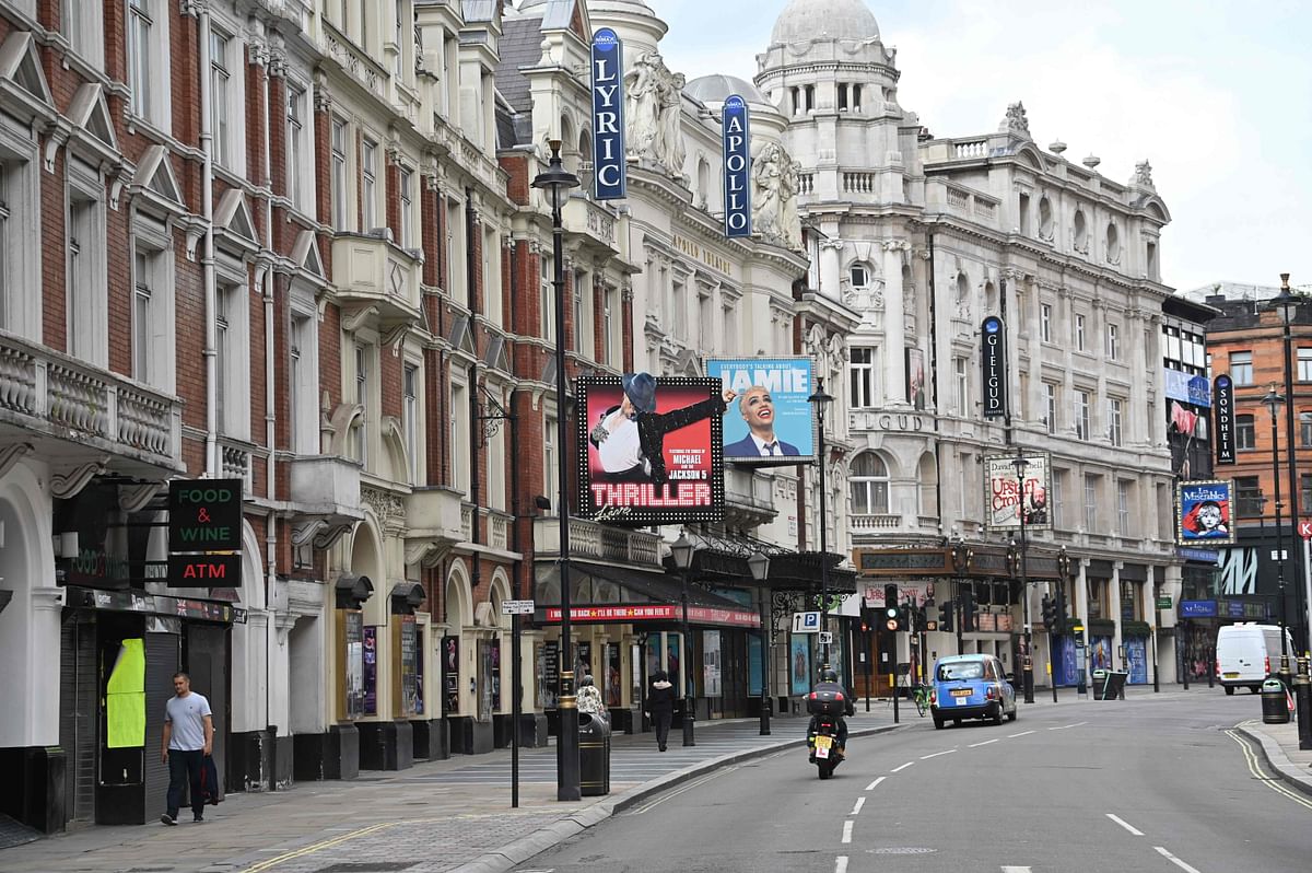 Pedestrians walk past the Lyric (L) and Apollo Theatres, which would be showing 'Thriller Live', and 'Jamie', but are closed down as part of the COVID-19 pandemic. Credit: AFP Photo