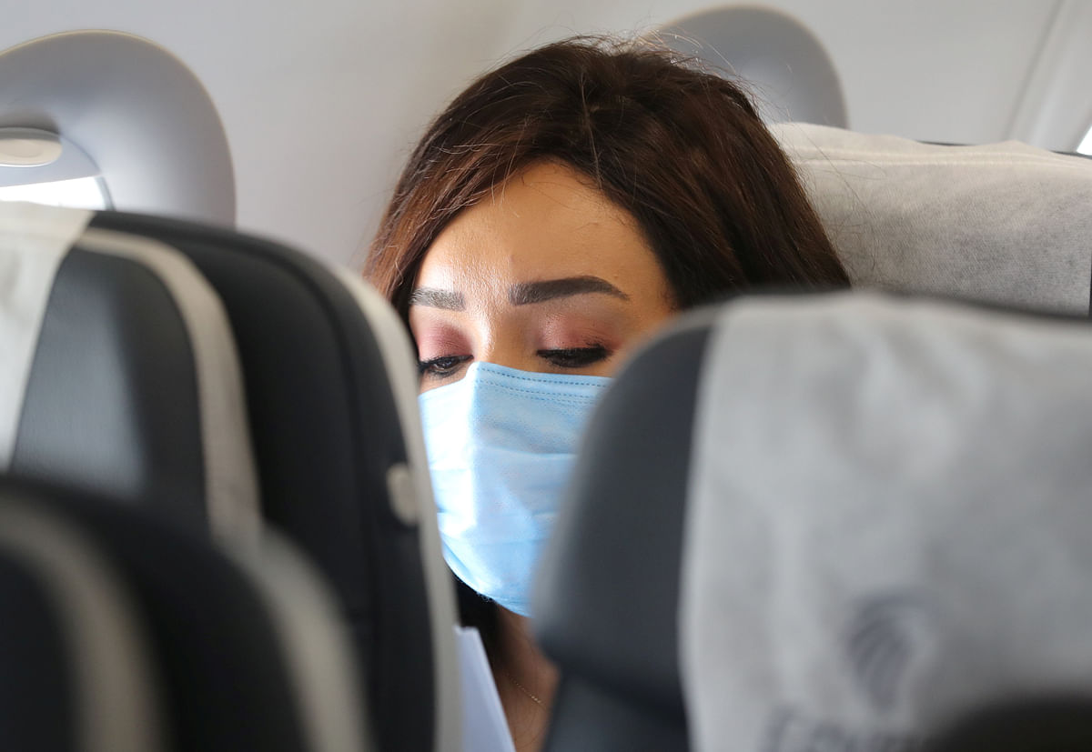 A traveller wears a protective face mask on a plane, following an outbreak of the coronavirus disease. Credit: Reuters Photo