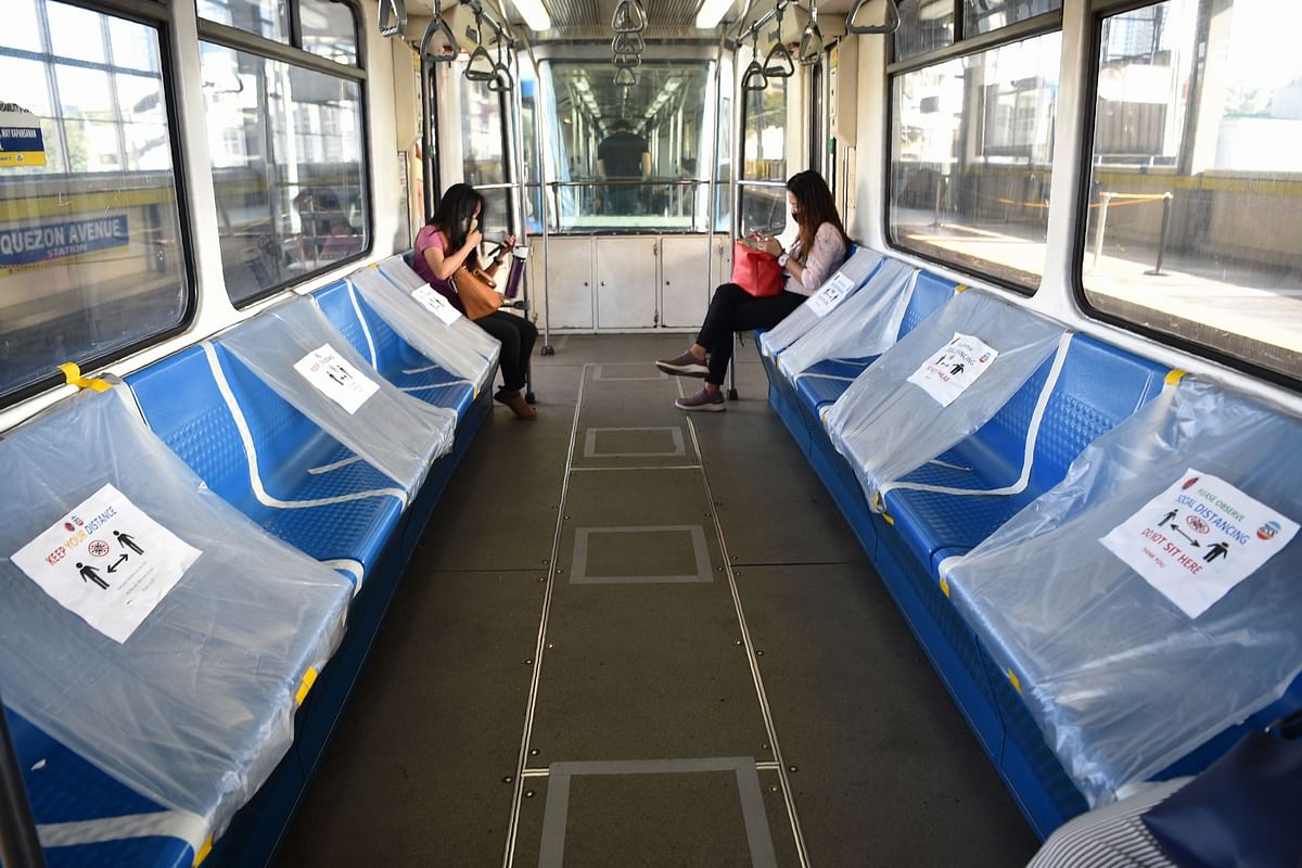 Passengers travel on a train, usually packed during rush hour, with plastic sheets spacing out seats to ensure social distancing, in Manila