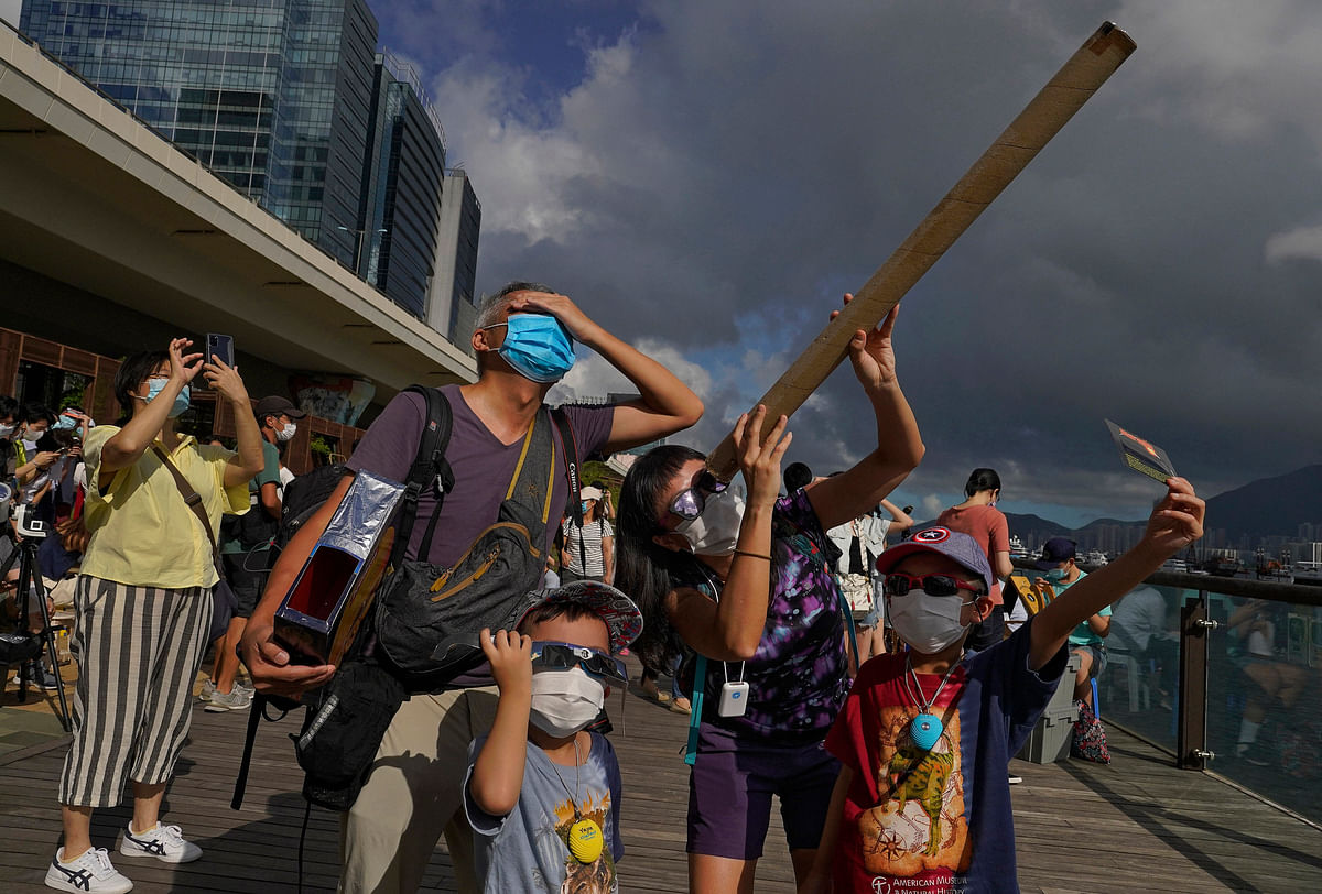 People watch a solar eclipse at a waterfront in Hong Kong. Credit: AP Photo