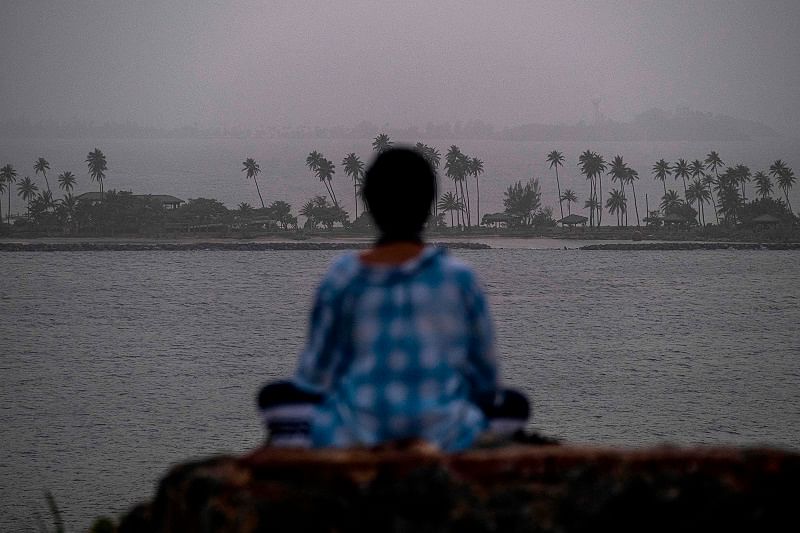 A woman meditates as a vast cloud of Sahara dust is blanketing the city of San Juan, Puerto Rico on June 22, 2020. - An expansive plume of dust from the Sahara is traveling westward across the Atlantic Ocean and is expected to reach the Caribbean and parts of the United States later this week. Credits: AFP Photo