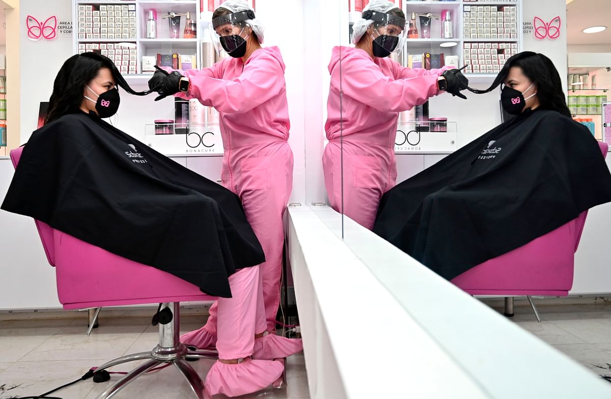 A stylist and a customer wear protective equipment as a preventive measure against the COVID-19 coronavirus, at a beauty salon in Bogota. Credits: AFP Photo