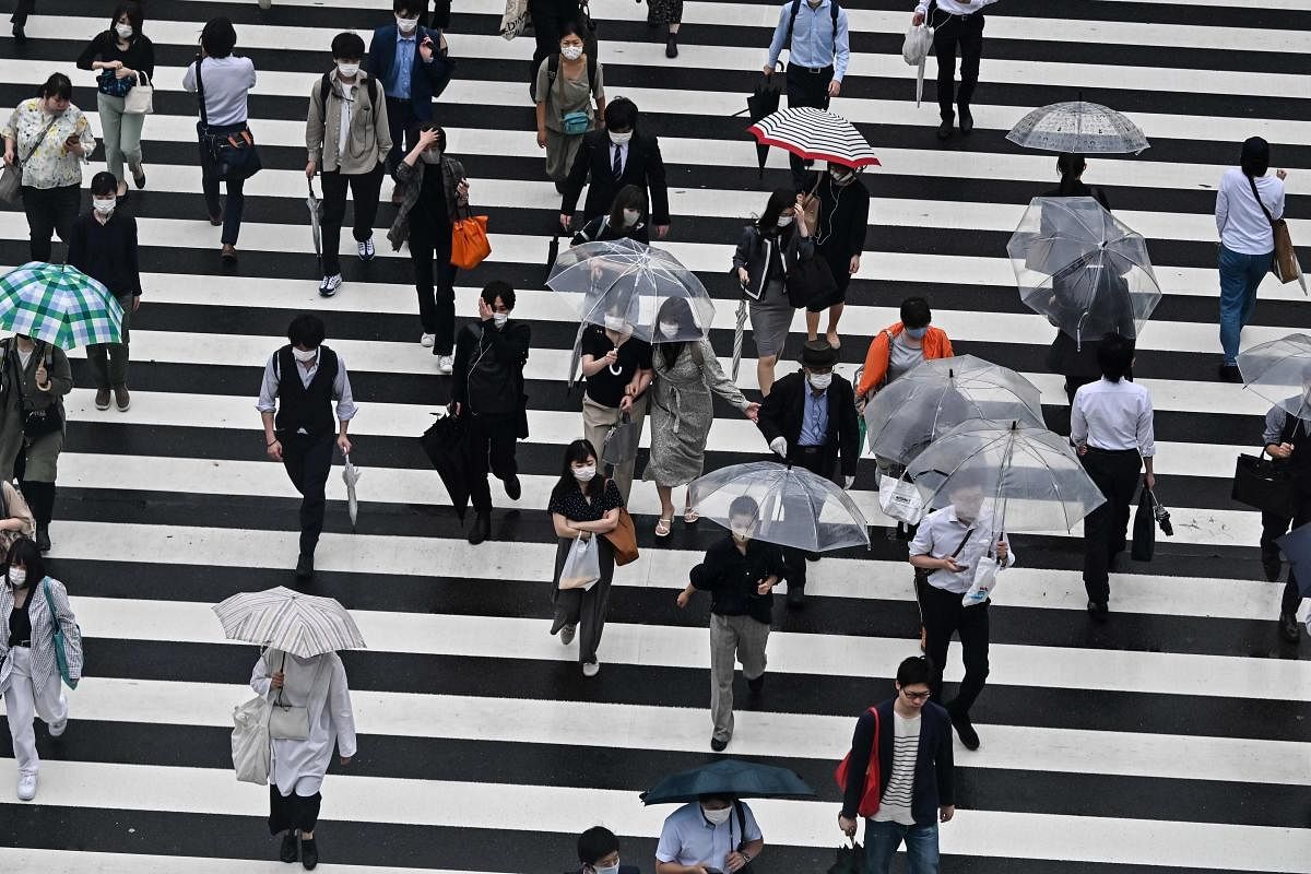 Pedestrians walk on a zebra crossing during a rainy morning outside Shinjuku station in Tokyo. Credit/AFP Photo