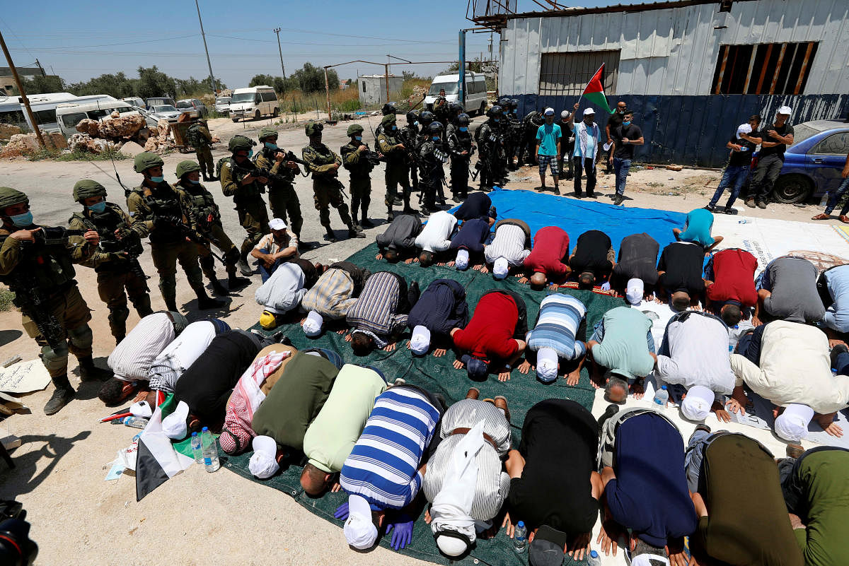 Palestinians perform Friday prayers as Israeli forces gather during a protest against Israel's plan to annex parts of the occupied West Bank, in Haris June 26, 2020. Credit/Reuters Photo