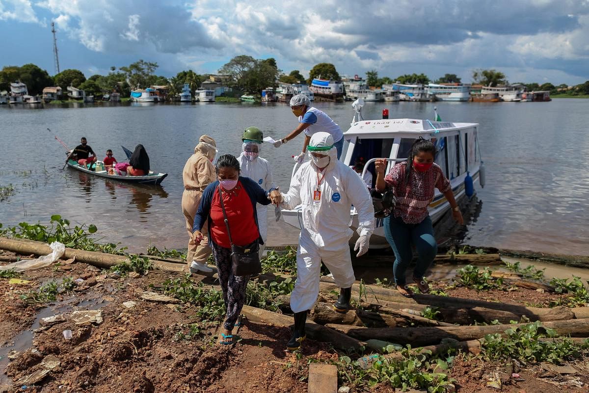 Health professionals help patients with symptoms of the new coronavirus brought on a boat ambulance from Vila Amazonia community upon their arrival in Parintins, Amazonas state, Brazil. AFP
