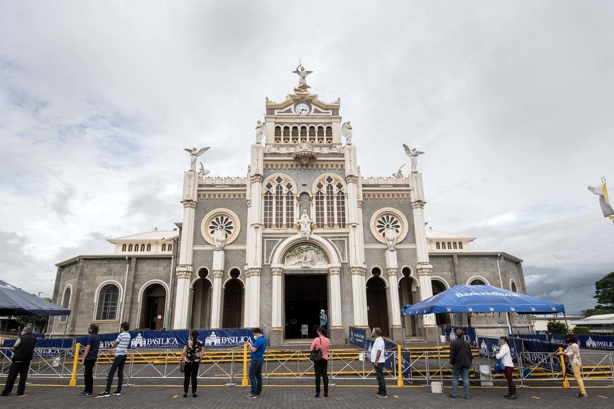 People queue outside the Basilica de los Angeles in Cartago, Costa Rica, amid the new coronavirus pandemic. - The third phase of measures against the spread of COVID-19 began Sunday in Costa Rica, allowing assistance to churches with a minimum distance of 1.8 meters between each person and with a maximum of 75 people, all with masks. AFP