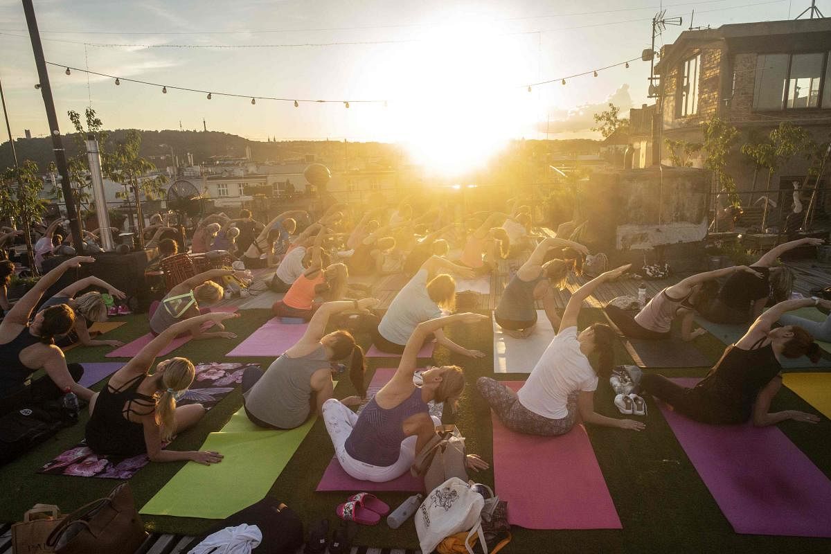People take part in a yoga session on the roof of Lucerna Palace as the sun goes down in Prague. Credit/AFP Photo