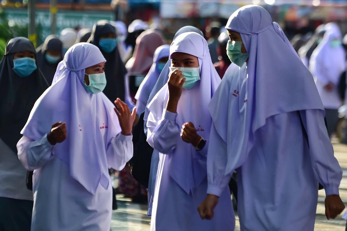 Muslim students wearing face masks talk in the Attarkiah Islamic School in the southern Thai province of Narathiwat on July 2, 2020, as schools across Thailand reopened after being temporarily closed to concerns about the COVID-19 novel coronavirus. Credit/AFP Photo