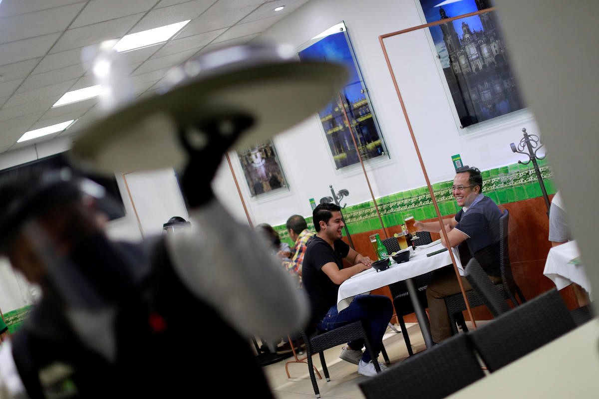 Customers are seen through acrylic partitions for social distancing at Los ponchos restaurant during the start of the gradual reopening of commercial activities, as the coronavirus disease (Covid-19) outbreak continues, in Mexico City. Credit: Reuters