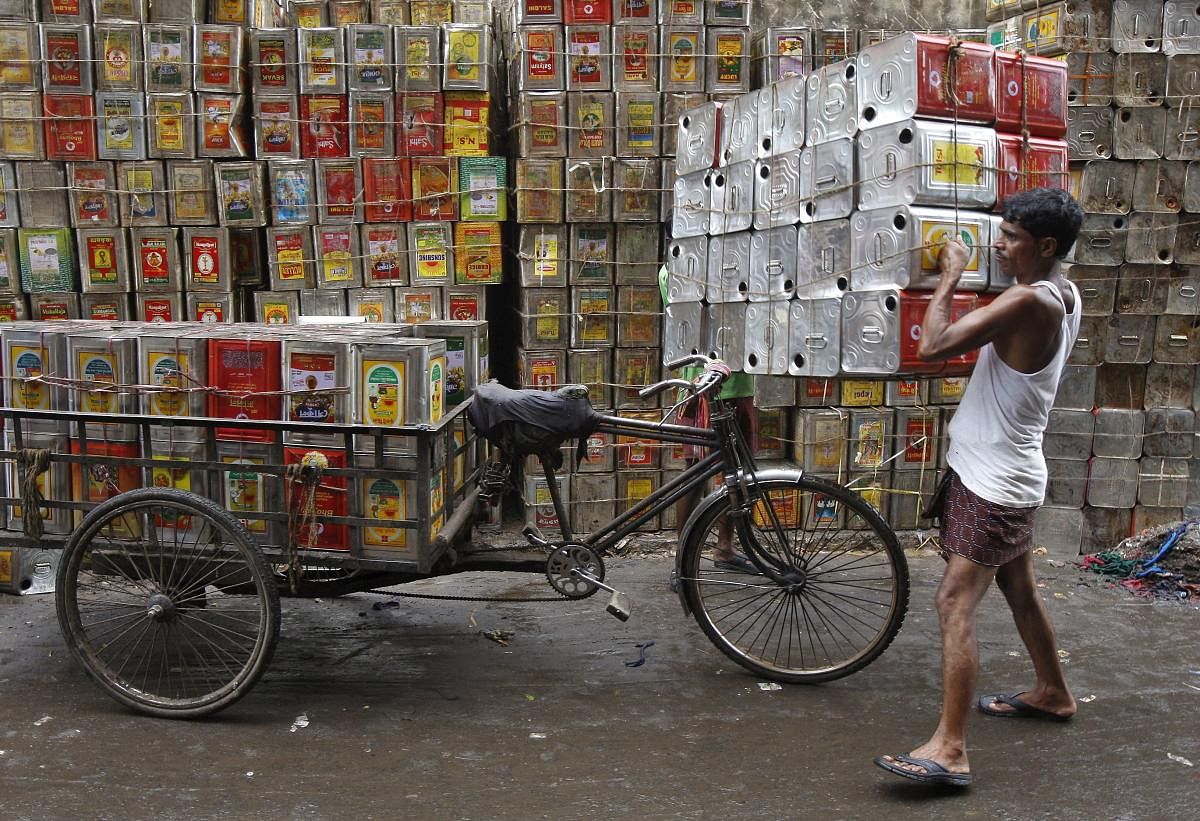 A man loads empty containers of edible oil onto a tricycle at a roadside in Kolkata, India. Credit: Reuters