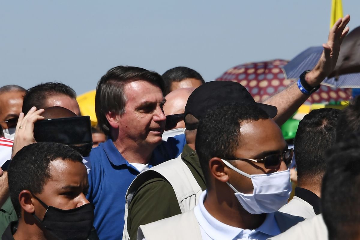 March 15 - Ignoring medical advice to quarantine, Bolsonaro takes selfies with supporters at a rally in Brasilia. Credit: AFP