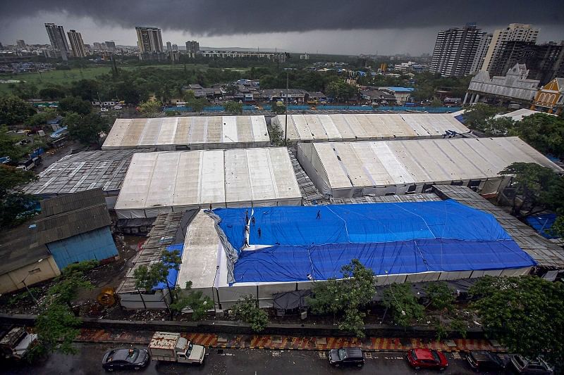 orkers cover the roof of a newly constructed COVID-19 care centre with tarpaulin for protection from rain water, at Dahisar in Mumbai. Credits: PTI Photo
