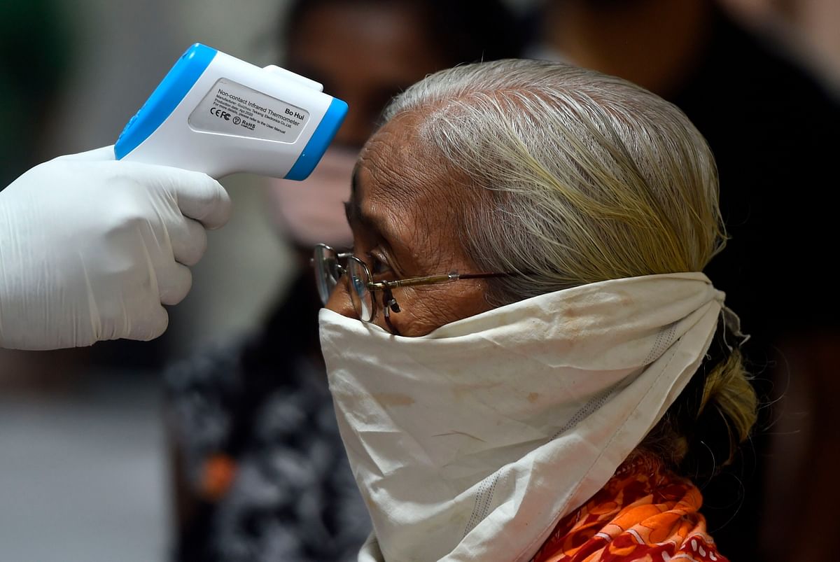 A medical volunteer takes temperature reading of a woman during a medical screening for the COVID-19 coronavirus, at a residential society in Mumbai. Credits: AFP Photo
