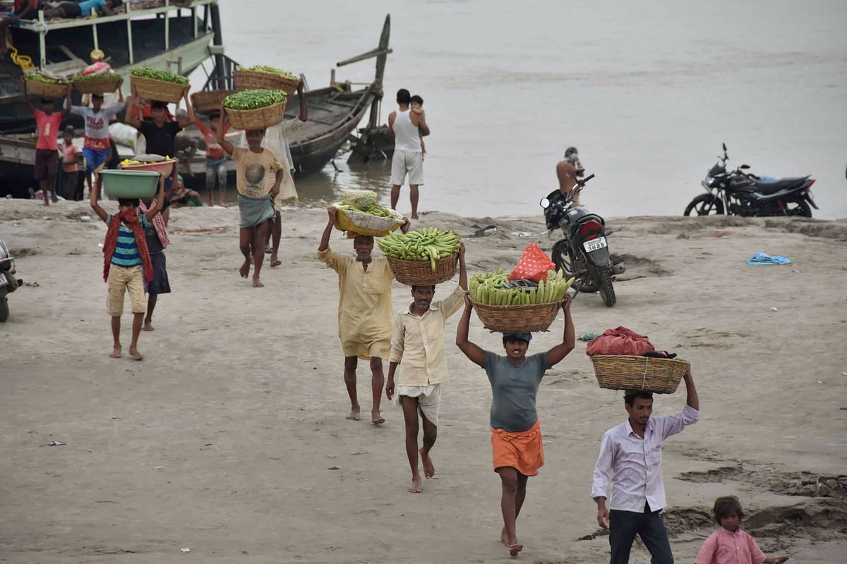 Farmer carry vegetables to a wholesale market after arriving at a Ganga ghat by a boat during the complete lockdown following surge in COVID-19 cases, in Patna. Credits: PTI Photo