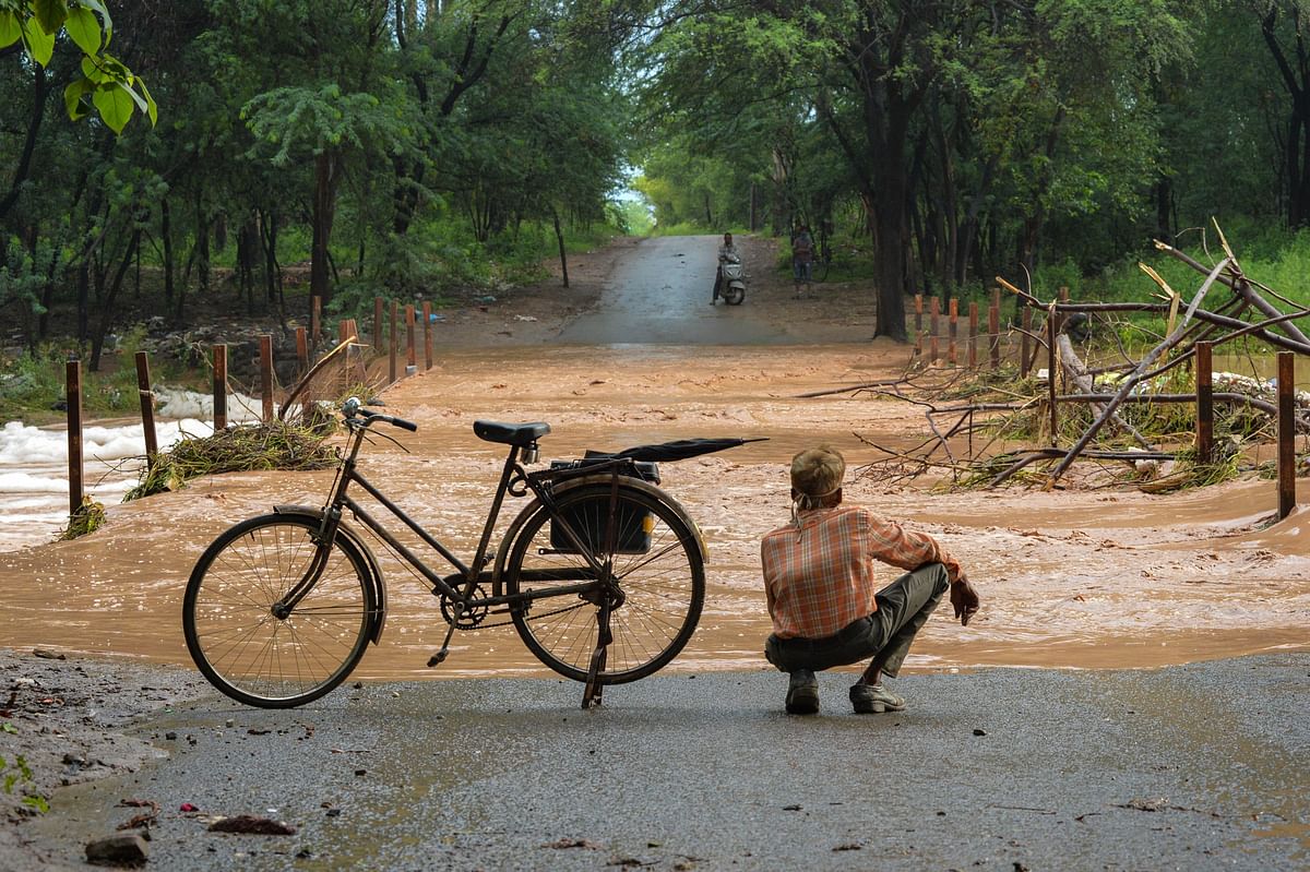 A cyclist waits to cross an inundated low-lying part of a road after heavy overnight rains, near Chandigarh. Credits: PTI Photo
