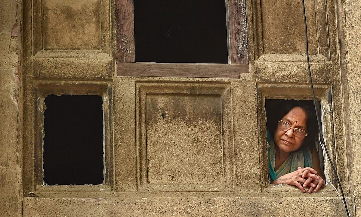 An elderly woman looks outside from a window of her house during Unlock 2.0 in Kolkata. Credits: PTI Photo