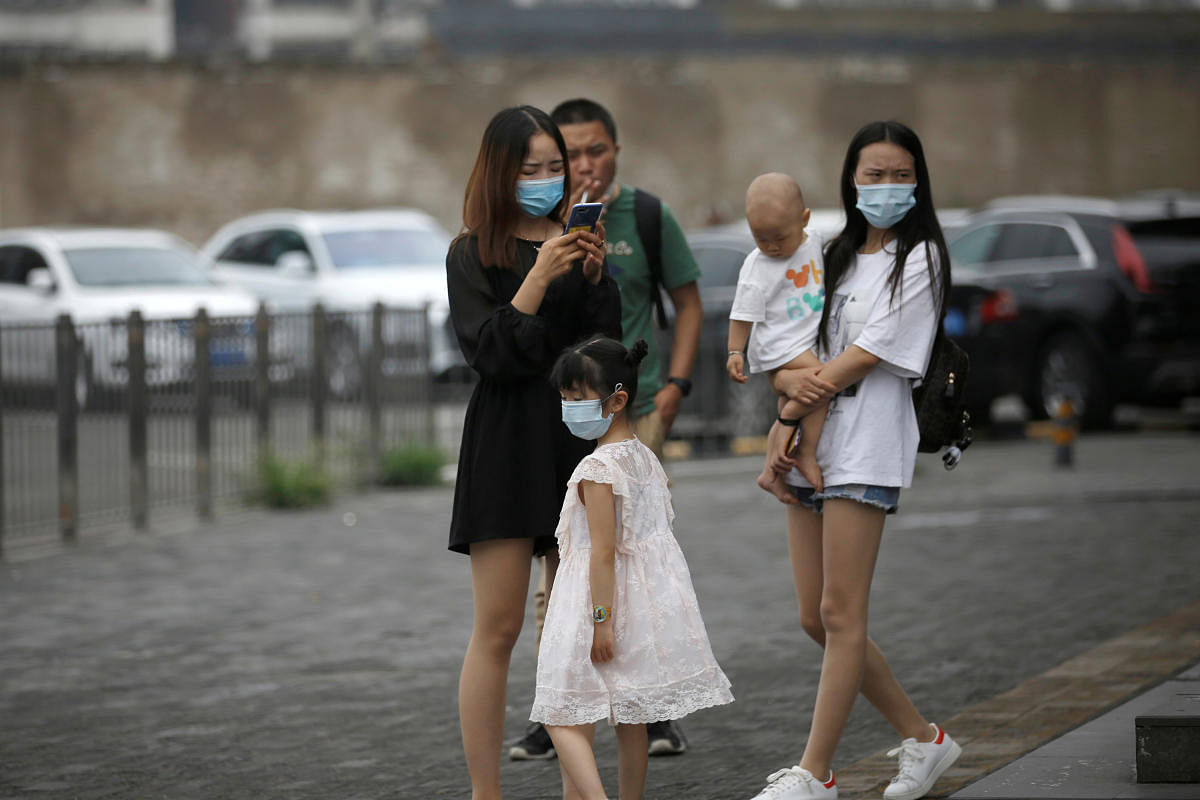 Women and a kid wearing face masks are seen on a street, following the outbreak of the coronavirus disease  Beijing (Reuters Photo)