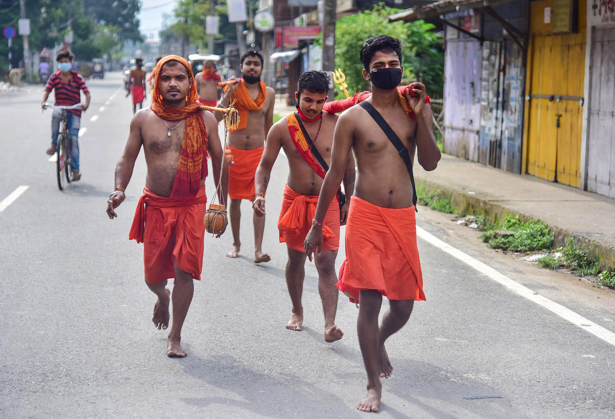 Kanwariyas walk down a road during their pilgrimage in the auspicious month of Shravan, in Nagaon district of Assam (PTI Photo)