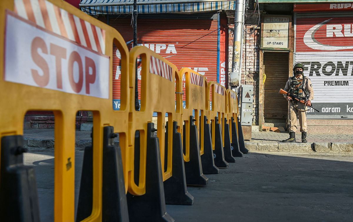 A security official stands guard on a blocked road after the authorities announced to re-impose lockdown from July 13 due to surge in COVID-19 cases, at Lal Chowk in Srinagar. Credits: PTI Photo