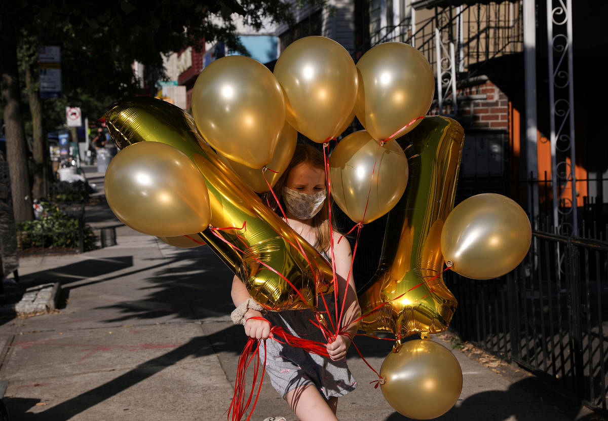 Lydia Hassebroek carries balloons for her birthday party in Brooklyn as New York slowly reopens during the continued outbreak of the coronavirus disease (Reuters Photo)
