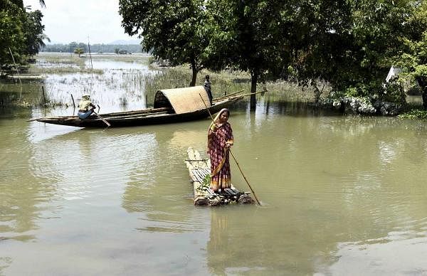 woman crosses a flooded area on a makeshift raft, at Bura Buri Village in Morigaon district, Saturday, July 4, 2020. Credit: PTI Photo