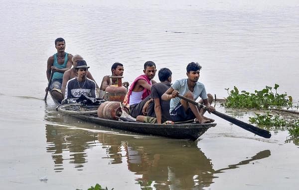 Villagers cross a flooded area by a boat, at Sildubi village in Morigaon district of Assam, Sunday, July, 2020. Credit: PTI Photo